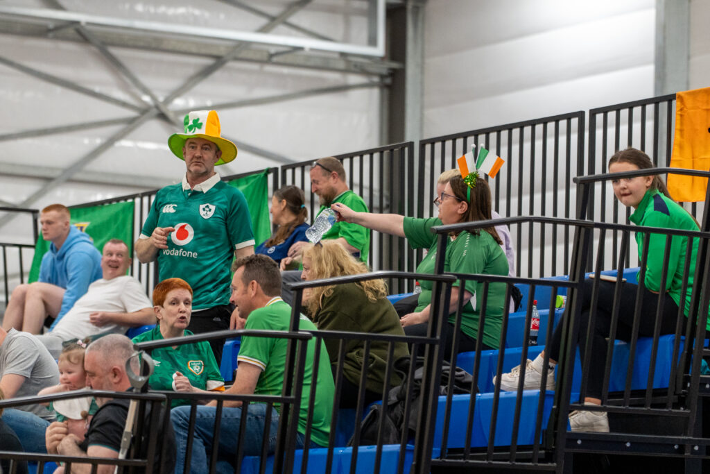 Supporters watching a powerchair football match from the sideline.