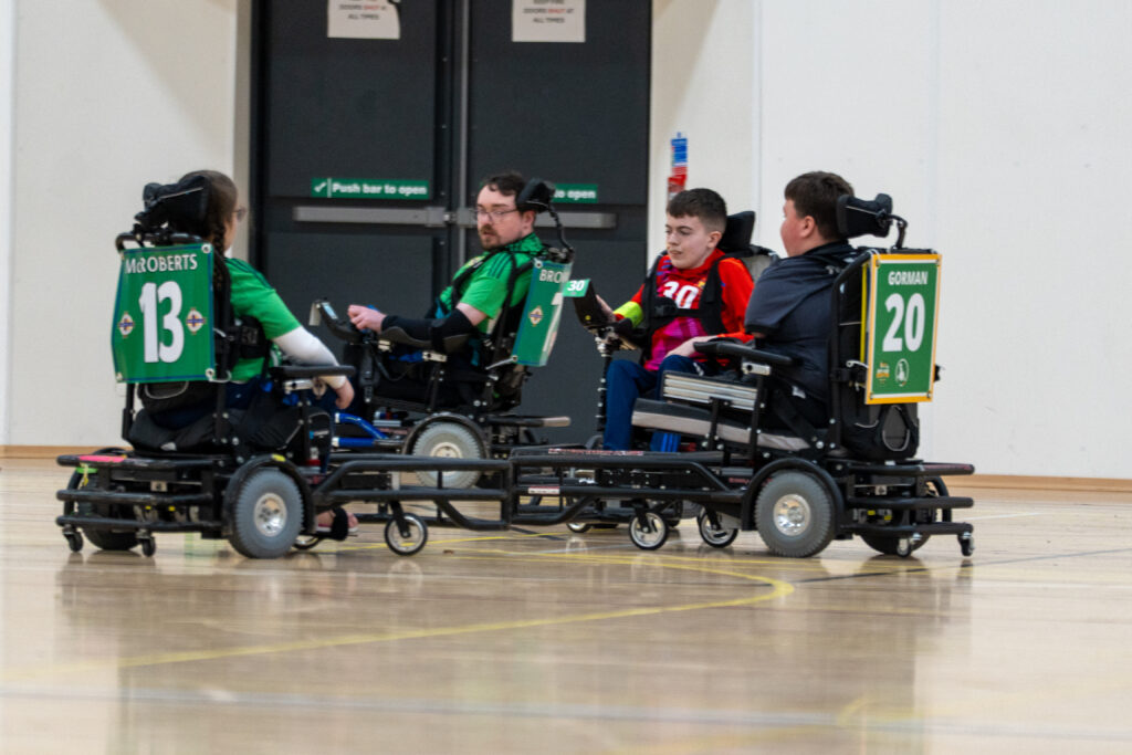 Powerchair football players competing for the ball during a match.